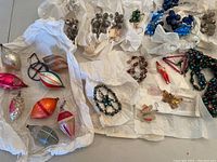 Wide view of multiple antique German Christmas ornaments spread out on white tissue paper including glass ornaments and beaded garlands.