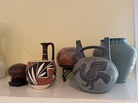Front view of the full assortment showing six pottery items on a mantle against white wall.