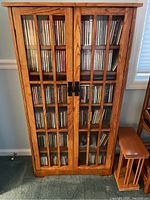 Straight-on photo of wooden cabinet showing glass paneled double doors filled with CDs