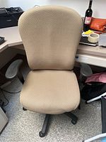 Front view of the beige office chair showing padded backrest and seat with black armrests and base.