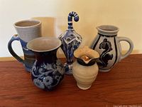 All five pottery items grouped together on a wooden surface under soft lighting.