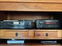 Wide view showing Onkyo CD player on left and Sony stereo receiver on right placed on wooden shelves.