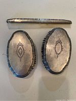 Top view of the sterling silver comb and two ornate brushes showing engraved decoration