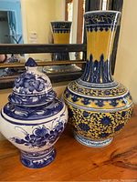 Ginger jar and urn placed side by side on a wooden surface with a mirror in the background.