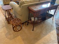 Full view of four wicker rattan furniture items including console table, side table magazine rack, small plant stand and stool beside a couch.