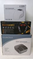 Photo of three massager boxes stacked: RodSky Knee Massager on top, 7WOQW Neck Massager in middle, Mountrax Foot Massager bottom box