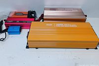 Four power inverters and battery charger laid out; large orange 3000W inverter in front