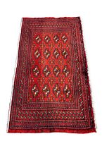 Overall view of the rectangular wool rug in red tones with repeating polygonal gul design.