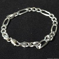 Full view of the bracelet laid in a circle on a black background showing whole chain and clasp.