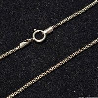 Close-up of the sterling silver chain's clasp and link details on a black background.
