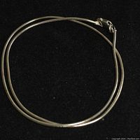 Full view of the 14 inch sterling silver chain coiled in a circle on a black background.