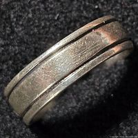 Close-up view of the sterling silver ring showing surface texture, scratches, and design details.