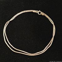 Full view of the 16-inch silver chain necklace arranged in a circle on black background to show length and clasp