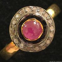 Close-up photo of the ring showing the top view with ruby and diamond halo.