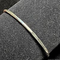 Side view of sterling silver bangle showing texture and shape