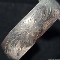 Close-up view of the floral engraving detail on the bracelet showing the craftsmanship and pattern.