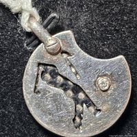 Close-up of the back side of the sterling silver pendant showing golfer cut-out and golf ball detail.