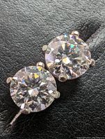 Pair of round brilliant moissanite stud earrings on black background