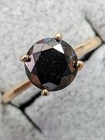Top view of ring showing round black diamond in four-prong setting