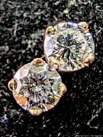 Close-up front view of both round brilliant cut diamonds set in four-prong 14k white gold on black background