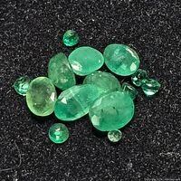 Loose emerald gemstones in mixed shapes and sizes on black fabric