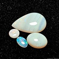 Four opals placed on black fabric background showing different shapes and color play.