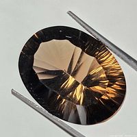 Close-up image of an oval-shaped optic cut smokey quartz gemstone showing facets and smoky brown coloration.