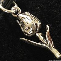 Close-up of silver rose pendant showing detailed bud, stem, and leaves