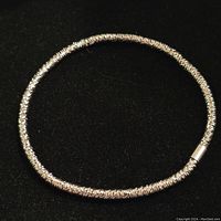 Photo showing the full view of the sterling silver adjustable bracelet coiled in a circular shape on a black background.