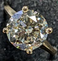 Close-up front-facing view of ring showing round brilliant cut diamond in four prong setting