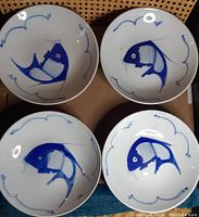 Four low rimmed bowls with blue koi fish artwork, viewed from above