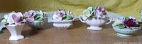 Five Thorley China floral porcelain figurines displayed side by side with various flower arrangements in small dishes or containers.