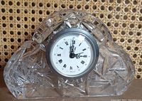 Front view of the crystal desk clock showing the cut crystal housing and round clock face with Roman numerals.