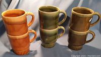 Three pairs of vertically stacked drip glaze mugs in orange, green, and brown colors.