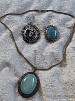 Photo showing all three pieces of jewelry: one necklace with pendant and two brooches with distinct cabochon stones