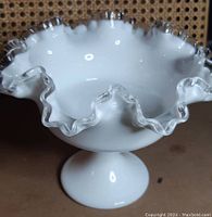 Front view showing the ruffled edge with clear glass trim and pedestal base.