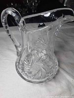 Full side view of the pinwheel crystal carafe showing handle and cut design.