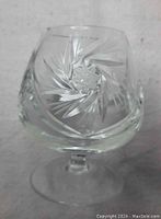 Close-up of one pinwheel crystal brandy glass showing detailed starburst and leafcut pattern