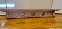 Long solid wood shelf with three heart cut-out details along the back panel, natural wood finish.