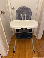 Front view of the Graco SimpleSwitch highchair with visible tray, padded seat, and metal legs.