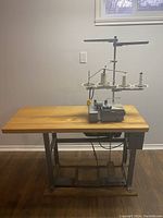 Full view of serger mounted on wooden tabletop and metal stand