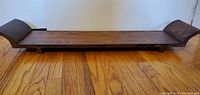 Espresso stained wooden shelf with curved ends placed on wooden floor