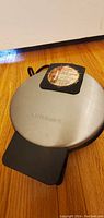 Closed waffle maker showing stainless steel top with Cuisinart brand embossed, integrated handle and control switch area.