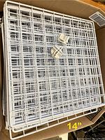 Several white wire cube panels stacked in a box with two white plastic cube connectors resting on top. Panels measure about 14 inches square.