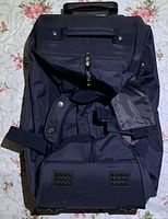 Top view of black multi-function travel bag showing main zipper compartment, handles, shoulder strap attachment, and external pockets.