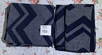 Folded blue quilt cover with geometric chevron pattern in navy and dotted design, front side view