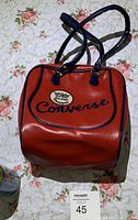 Red leather Converse bag with blue piping and handles shown from the front with visible All Star Champion logo patch.