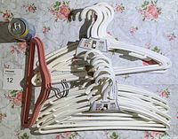 Photo of two packs of white plastic hangers with a can for scale and an additional set of pink hangers.