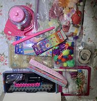 Wide view showing all craft tools and supplies spread out on table including yarn winder, pom poms, beads, ribbons, and artificial flowers.