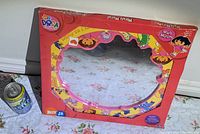 Front view of the boxed Dora the Explorer wall mirror showing red frame with character images and Nick Jr. branding.